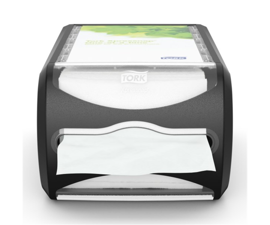 A black tabletop napkin dispenser with a single white napkin partially pulled out from the front slot. Tork Xpressnap® Counter Napkin Dispenser (7.5 in. x 5.7 in. x 12.1 in., 1/Case)